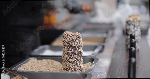 Preparing trdelnik a traditional chech street sweet food on a Christmas fair outdoors. Close-up video shot photo