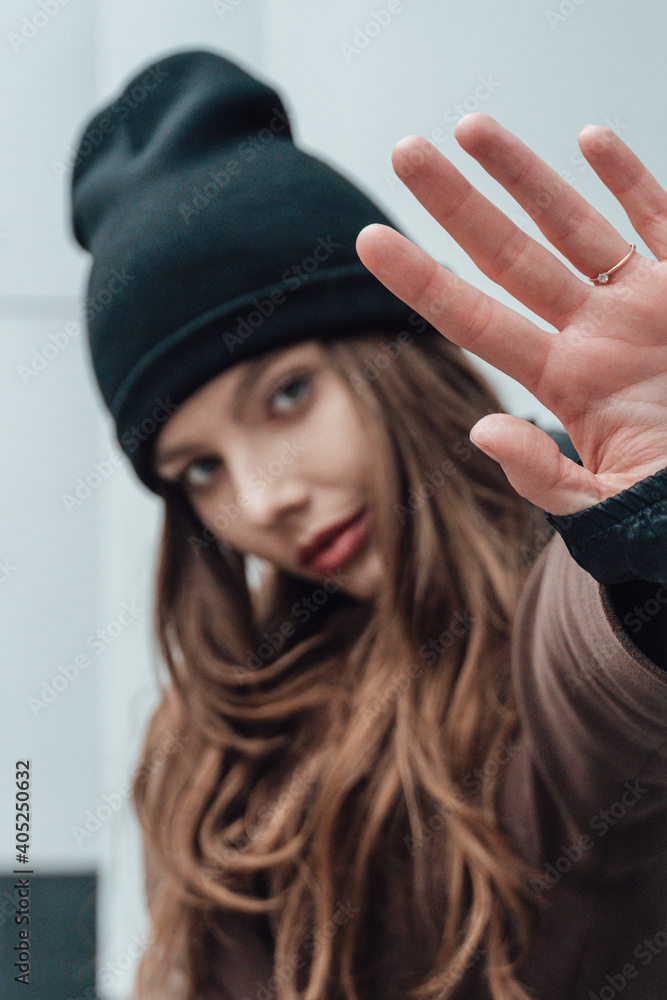 Selective focus portrait of young female model in hipster style hat and coat showing denial gesture with her hand. Selective focus portrait of young female model in hipster style hat and coat showing denial gesture with her hand.