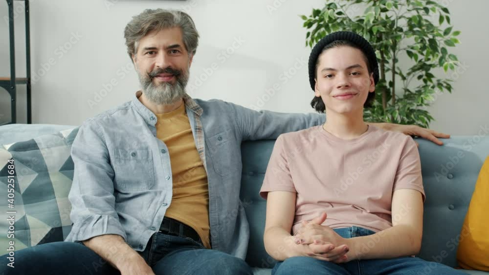 Portrait of happy family handsome mature father and teenage son sitting at home smiling looking at camera. Positive emotions and apartment concept. Portrait of happy family handsome mature father and teenage son sitting at home smiling looking at camera. Positive emotions and apartment concept.