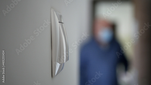Blurred Person in Background Wearing Medical Face Mask Enter in the Office and Push the Lights Switch