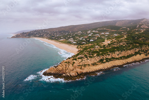 The Camarinal lighthouse on the Spanish Atlantic coast in Andalusia. An aerial view with a cloudy sky and haze in the air.