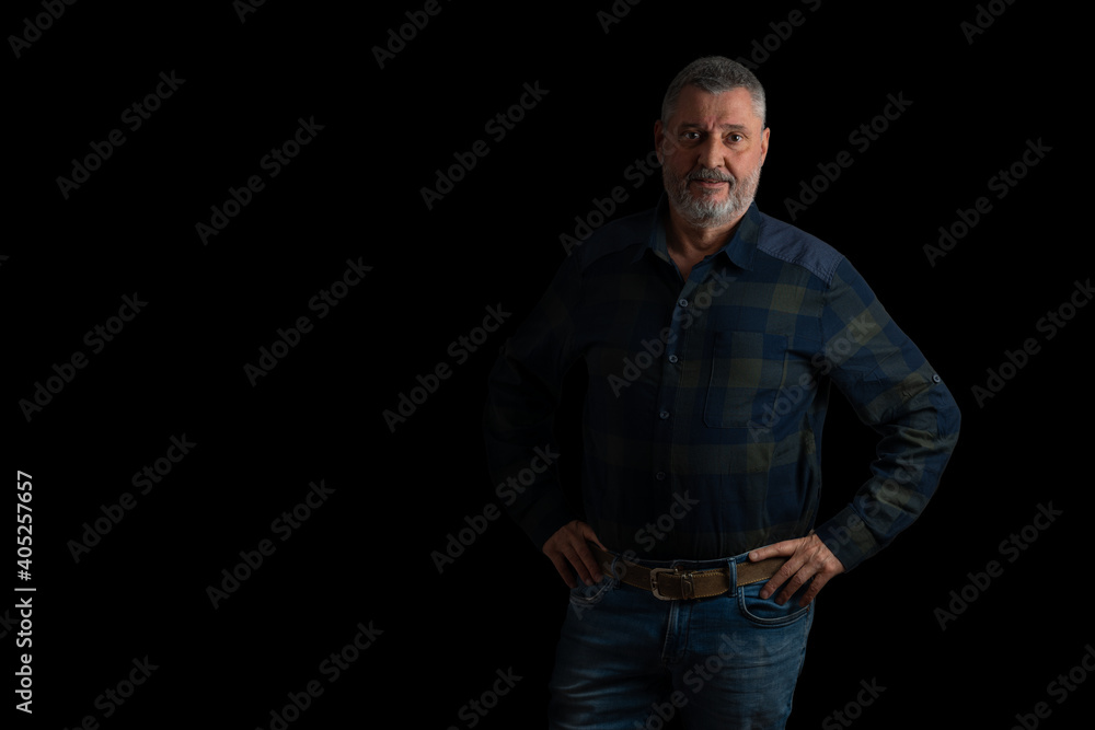 Portrait of a senior with a beard and gray hair. He is wearing a green and blue shirt. The light comes from the side. The motif is cut out against a black background. Portrait of a senior with a beard and gray hair. He is wearing a green and blue shirt. The light comes from the side. The motif is cut out against a black background.