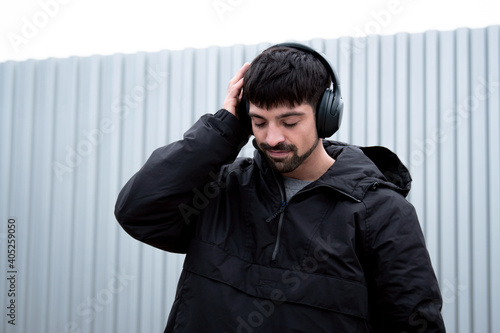Caucasian white man with listening to music with black warm clothes feeling and enjoying music with metallic gray photo
