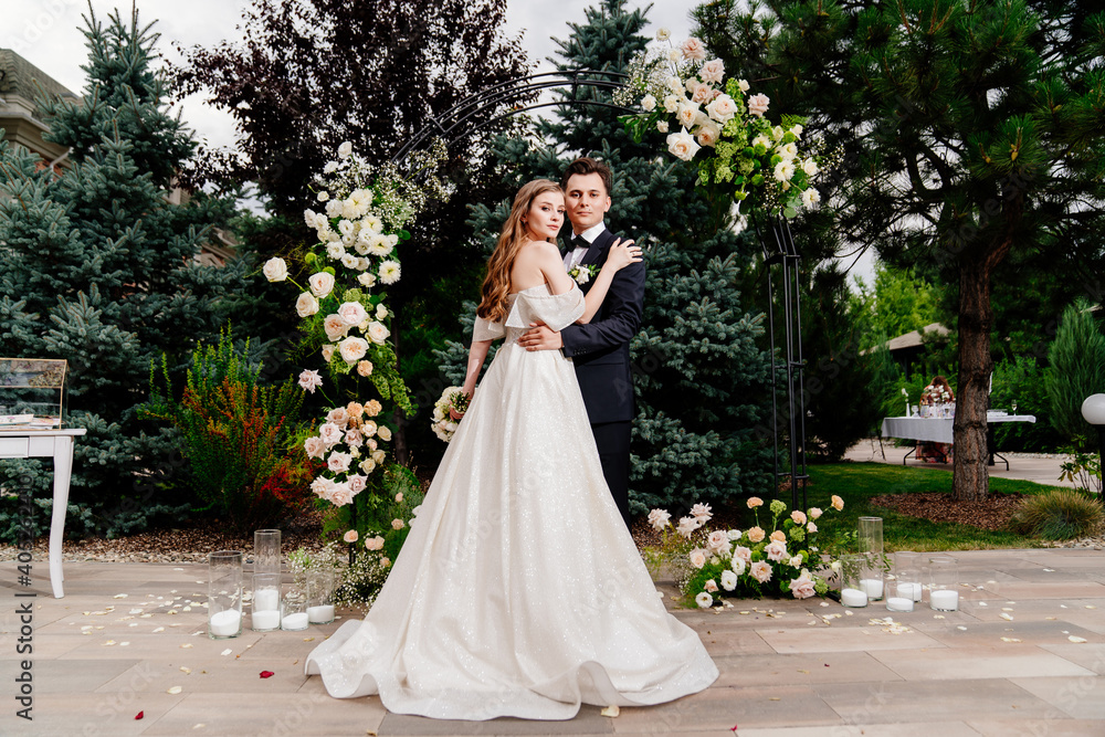 outdoor wedding ceremony in an arch of living flowers.Beautiful couple newlyweds