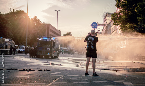 Fotografia Police water cannon in sunset light during G20 summit protests in Hamburg, Germa