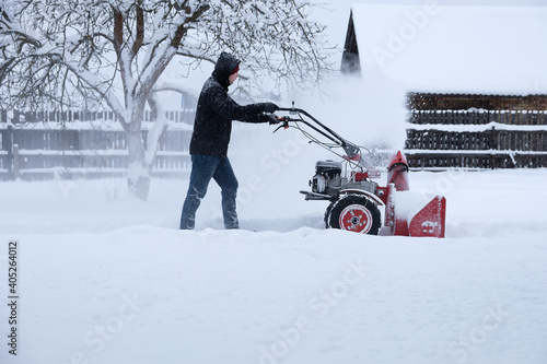 young man clearing snow in his backyard with wheeled snow blower