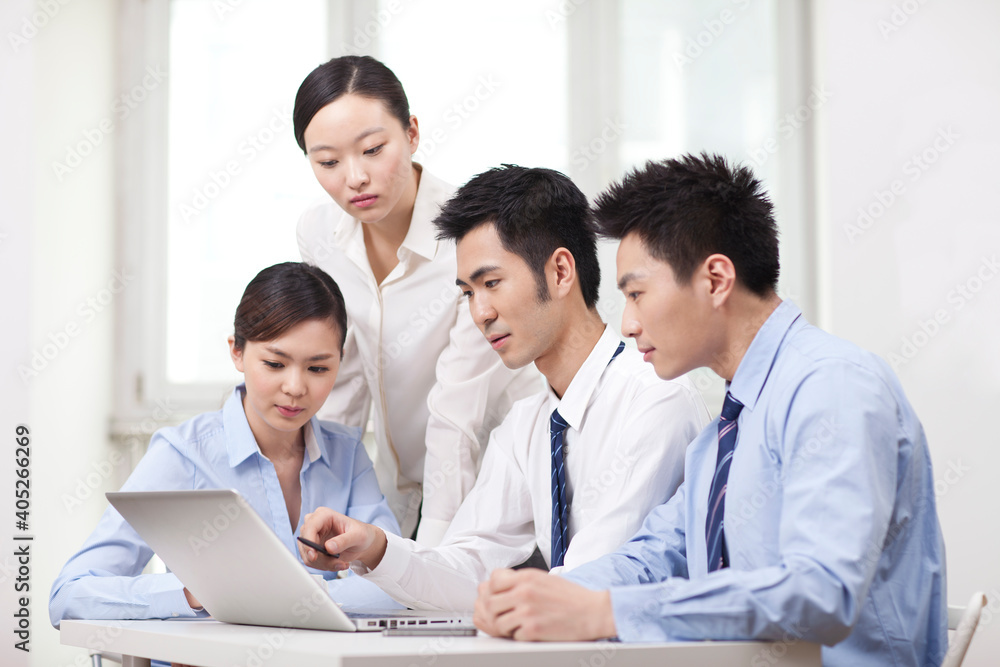 Group of businesspeople discussing working on computer Group of businesspeople discussing working on computer