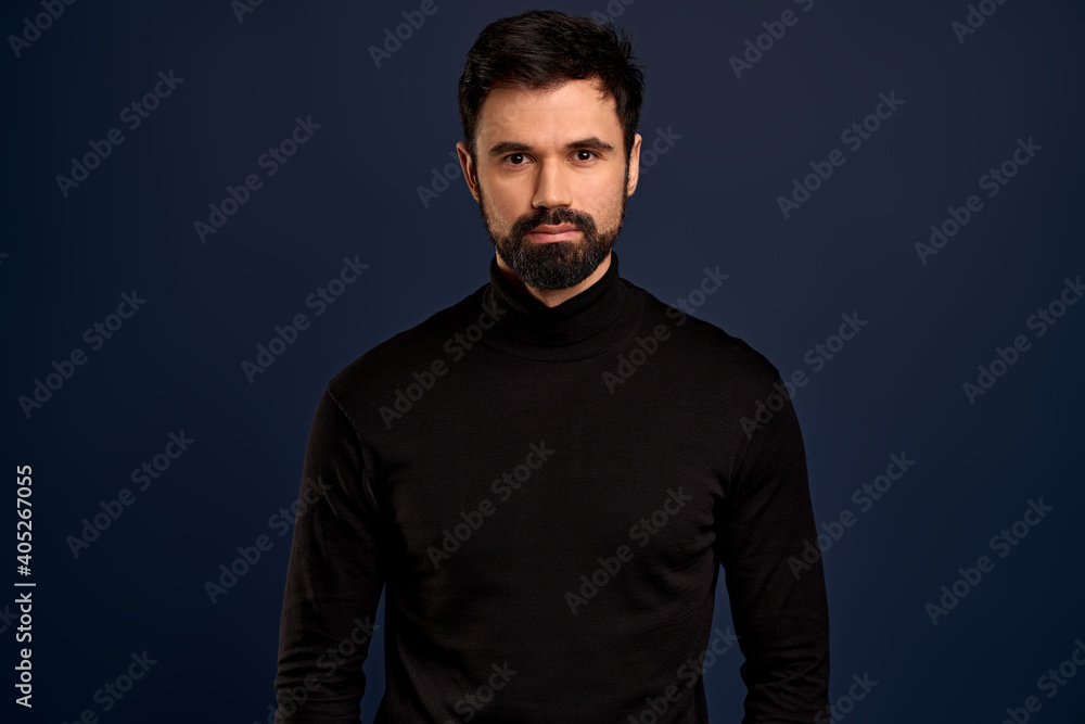 Fototapeta premium Confident good-looking male entrepreneur in black high neck sweater, smirk and self-assured, standing assertive. Handsome macho man