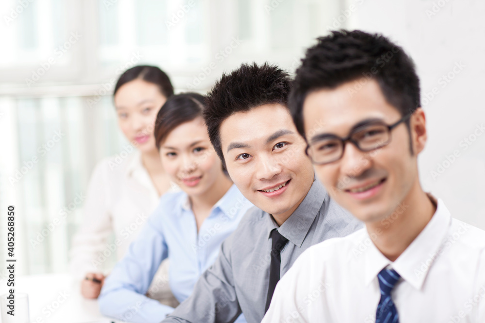 Executives sitting at conference table focus on woman in foreground Executives sitting at conference table focus on woman in foreground