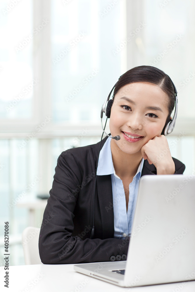 Young woman using laptop and wearing headset Young woman using laptop and wearing headset