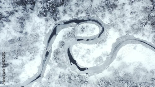 Top view s-curved frozen winding river in winter snowy forest
