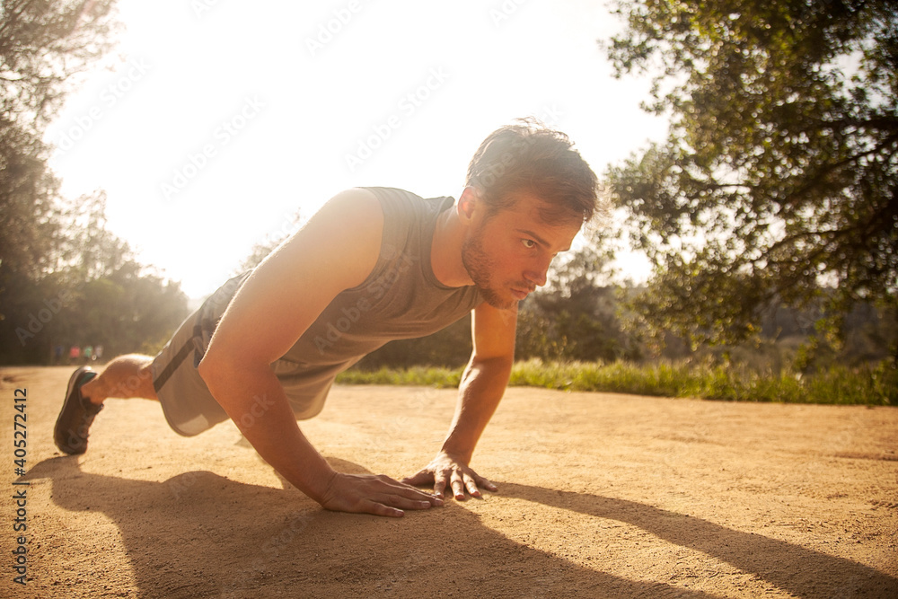 Athlete exercising while doing push-ups on footpath Athlete exercising while doing push-ups on footpath