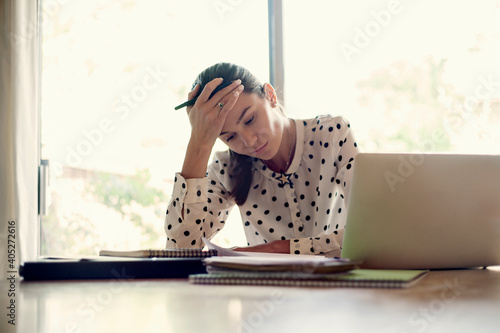 Tired businesswoman sitting with head in hands while working at office photo