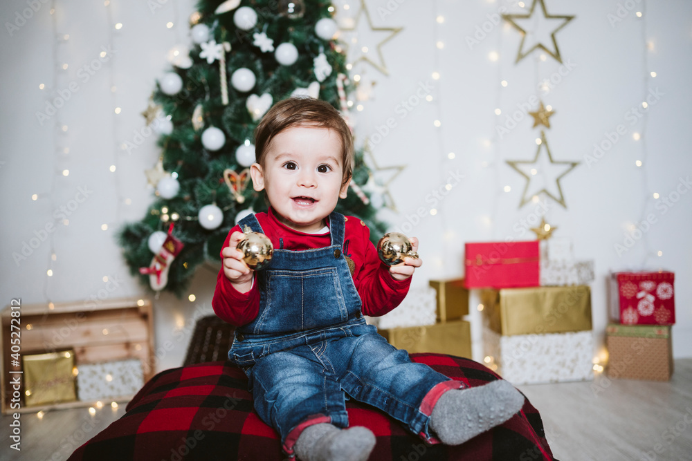 Happy baby boy playing with bauble while sitting at home during Christmas Happy baby boy playing with bauble while sitting at home during Christmas