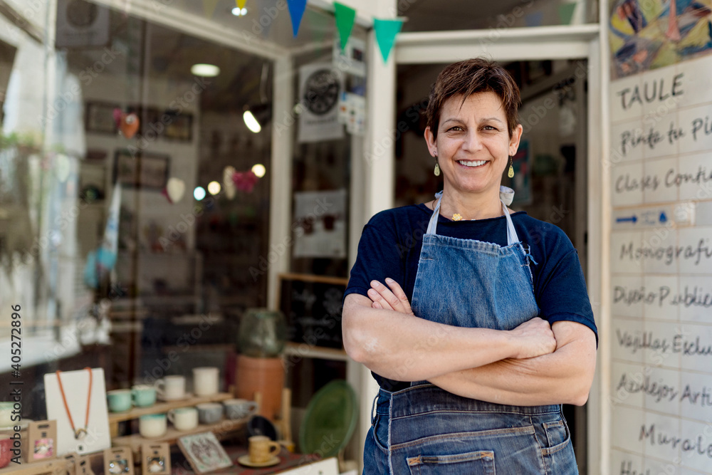 © Ezequiel Gimenez/Westend61 - Happy small business owner standing with arms crossed outside her store