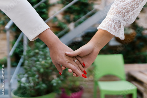 Teenage girl holding young bride's hand in garden photo