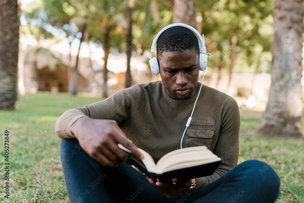 Male entrepreneur reading book while sitting on grass in park Male entrepreneur reading book while sitting on grass in park