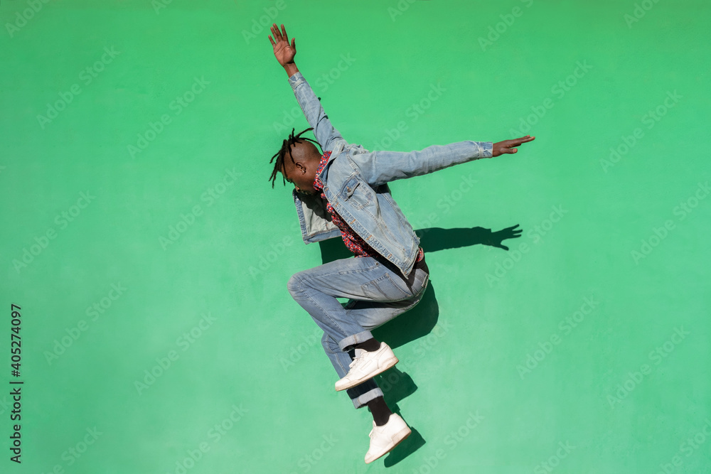 Young african man jumping up isolated on green colored background.