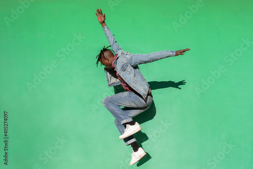 Young african man jumping up isolated on green colored background. photo