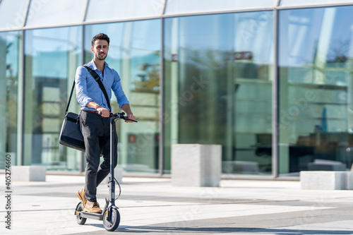 Businessman riding electric push scooter on footpath photo