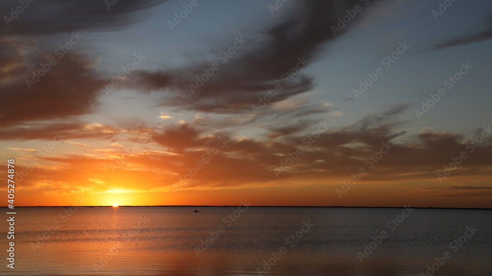 Sun drops to horizon during stunning sunset while kayak glides in Laguna Madre, along Texas gulf shore;  copy space