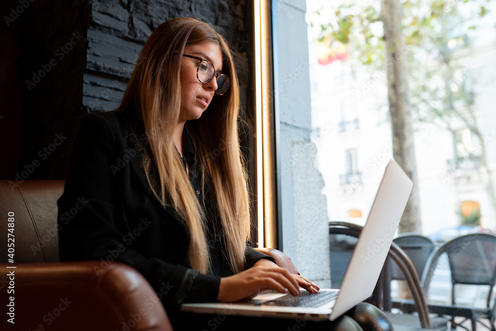 Young woman wearing eyeglasses using laptop while sitting at cafe Young woman wearing eyeglasses using laptop while sitting at cafe
