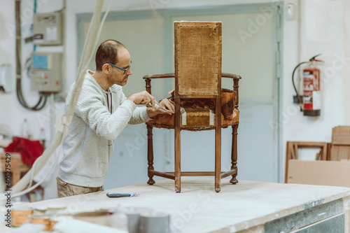 Expertise restoring wood chair while standing at workshop