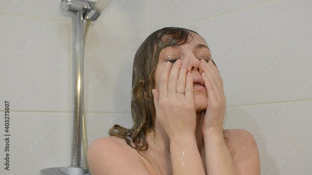 Young charming woman washes off mascara from her eyes in the shower Stock ビデオ | Adobe Stock