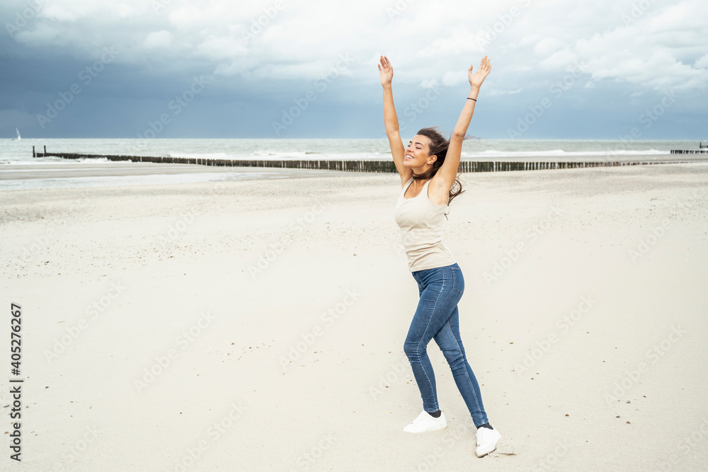 Young woman with arms raised dancing while dancing at beach Young woman with arms raised dancing while dancing at beach