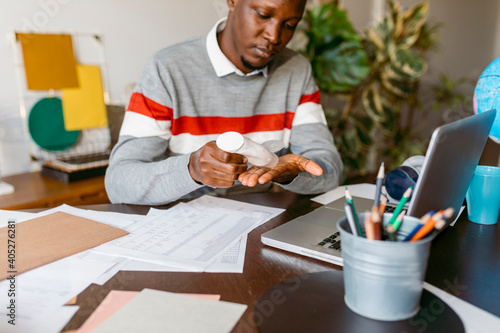 Male freelancer applying hand sanitizer during work from home photo