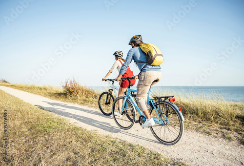 Man with backpack cycling bicycle with woman on footpath during sunny day photo