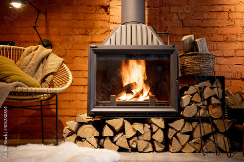 Fotografia Cozy fireplace with firewood in the loft style home interior with brick wall bac