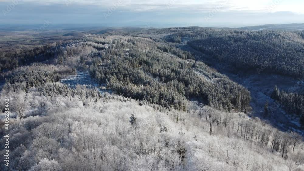 Aerial view of a frozen forest with snow covered trees at winter. Flight above winter forest in europe, top view. Poland, Wojcieszow, Kaczawskie gory. Winter background with forward parallax effect an Aerial view of a frozen forest with snow covered trees at winter. Flight above winter forest in europe, top view. Poland, Wojcieszow, Kaczawskie gory. Winter background with forward parallax effect an
