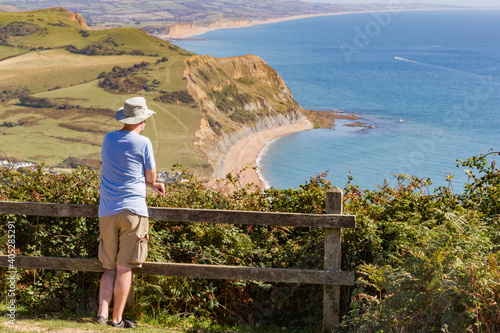 Фотография Person takes in the view out to sea from the top of Golden Cap in West Dorset, E