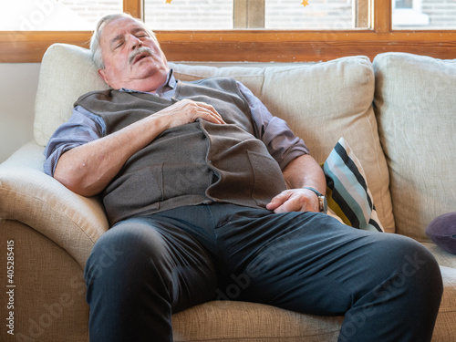 Valokuva Tired elderly male fall asleep on a comfortable couch in the living room