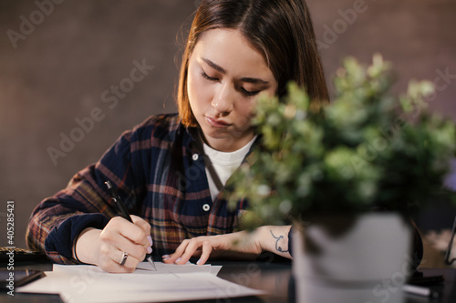 Asian girl trader working at home at the table, studying the chart