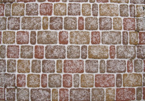 Paving stone texture covered with first snow. stone-block pavement background.