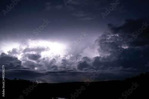 Strong lightning in and behind big towering thunderclouds