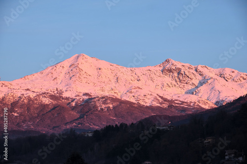 profile of a Piedmont alp overlooks the Po Valley immersed in a pink sunset