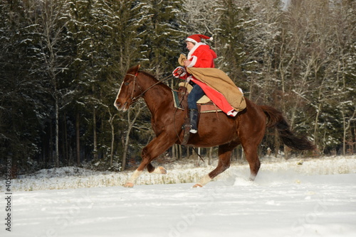 western santa. Weihnachtsmann auf einem Pferd im Schnee © Grubärin