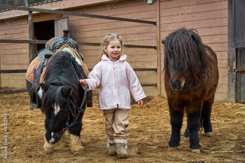 Girl and pony. Child and horses on the farm in the paddock. Equestrian school. Hippotherapy at the hipodrome.