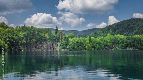 Panoramic view on beautiful waterfalls with reflections in lake. Green lush forest, Plitvice Lakes National Park UNESCO World Heritage in Croatia
