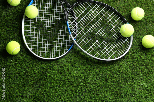 Tennis rackets and balls on green grass, flat lay. Space for text © New Africa