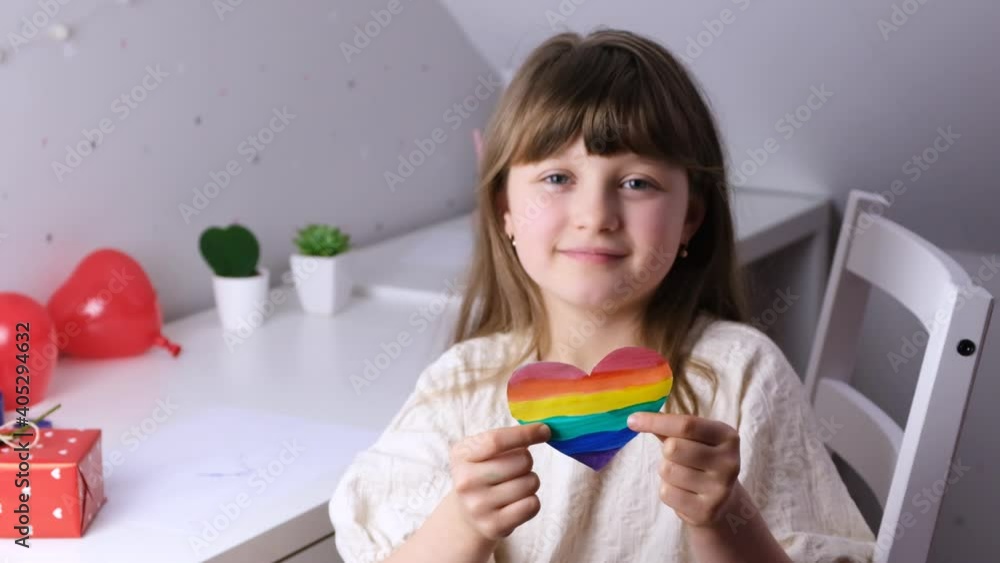 Valentine's Day. A cute Caucasian girl holding a rainbow-colored heart in front of her. Lgbt free love. Slow motions Valentine's Day. A cute Caucasian girl holding a rainbow-colored heart in front of her. Lgbt free love. Slow motions