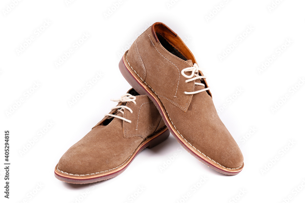 A pair of light brown suede chukka boots isolated on white background. Men's casual dress shoes with white laces laces. Top view, copy space for text, flat lay. A pair of light brown suede chukka boots isolated on white background. Men's casual dress shoes with white laces laces. Top view, copy space for text, flat lay.