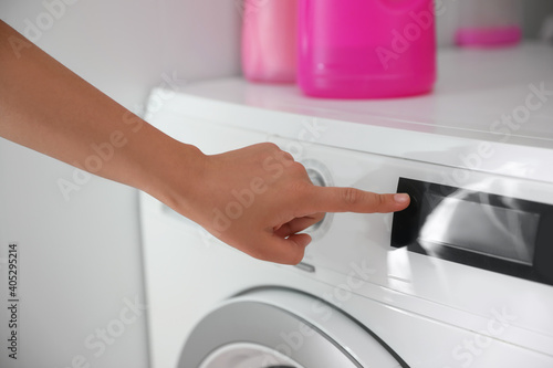Woman pressing button on washing machine in bathroom  closeup