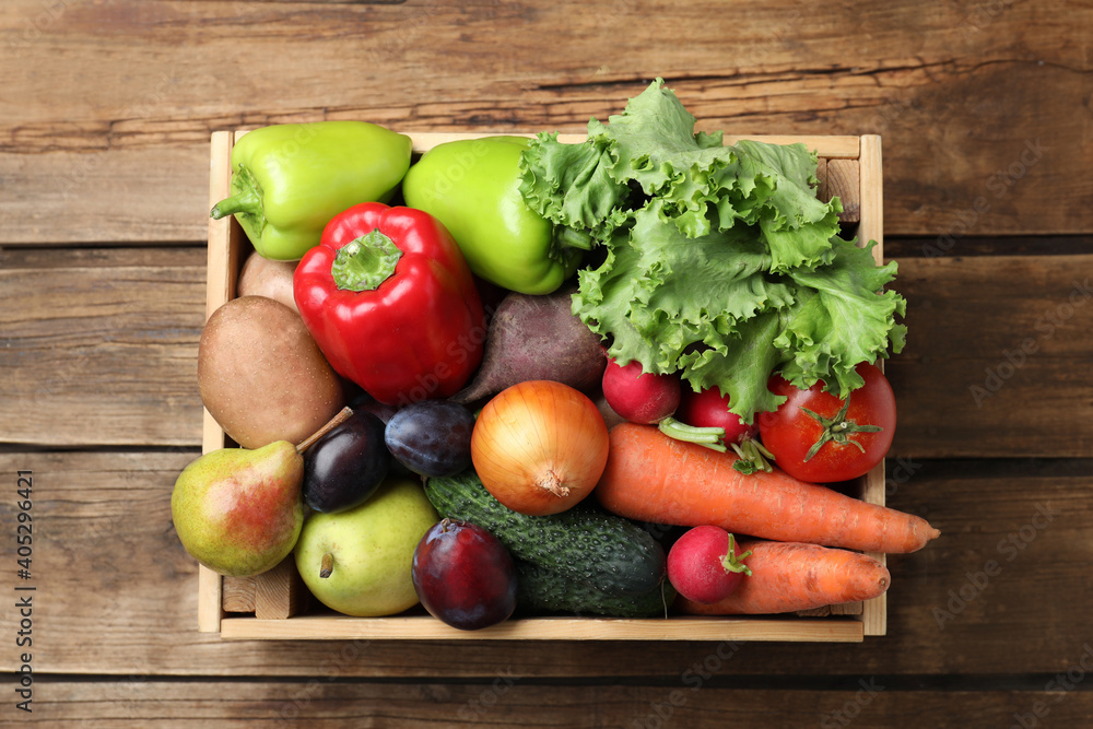Crate full of different vegetables and fruits on wooden table, top view. Harvesting time Crate full of different vegetables and fruits on wooden table, top view. Harvesting time