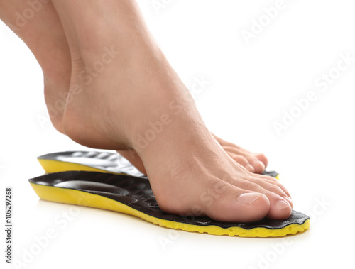 Woman fitting orthopedic insoles on white background, closeup. Foot care