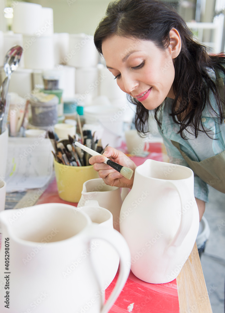 Female artist decorating pottery in studio Female artist decorating pottery in studio
