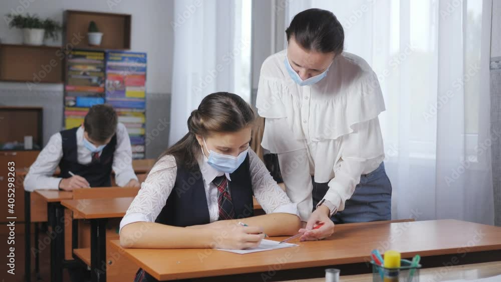 Training in medical masks during a pandemic. A teacher helps a student at school. Training in medical masks during a pandemic. A teacher helps a student at school.